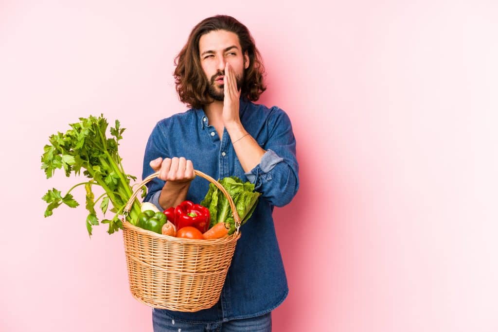 man holding fruit and veg produce looking suspicious