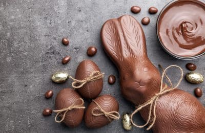 Delicious chocolate Easter bunny and eggs on wooden background